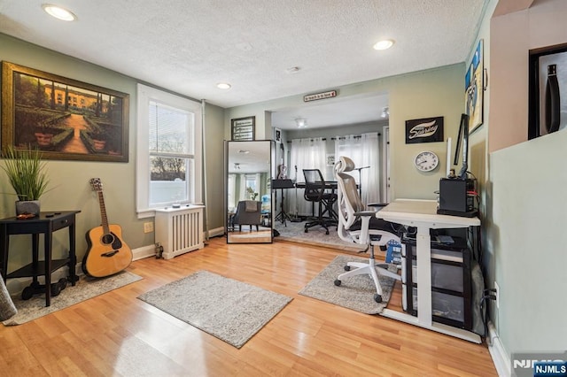 office with wood-type flooring, radiator, and a textured ceiling