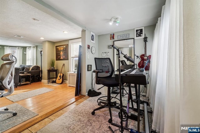 office space with hardwood / wood-style flooring, radiator heating unit, a textured ceiling, and a healthy amount of sunlight