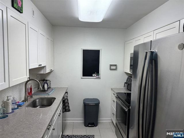 kitchen featuring white cabinetry, sink, stainless steel fridge, light tile patterned floors, and electric stove