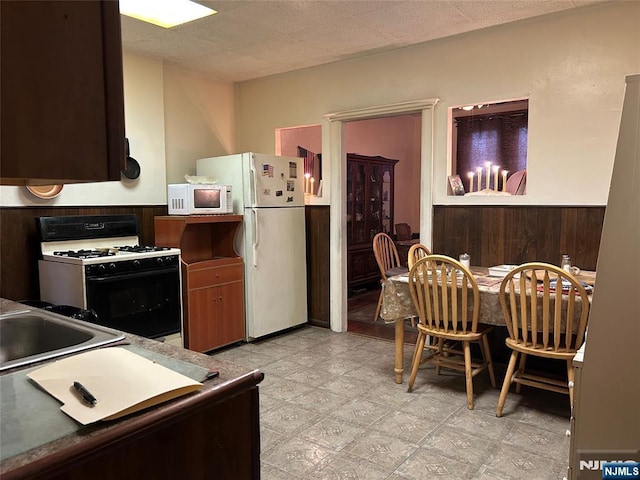 kitchen with sink, white appliances, and wood walls