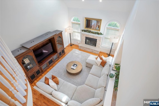 living area featuring a fireplace with raised hearth, baseboards, and wood finished floors