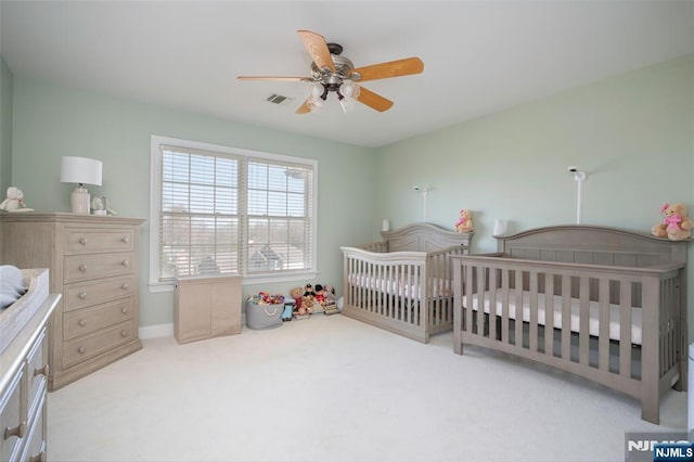 bedroom featuring carpet flooring, visible vents, baseboards, a ceiling fan, and a crib