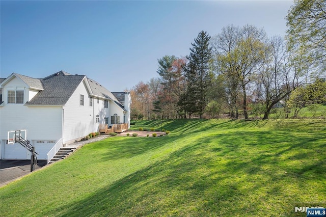 view of yard featuring a garage and aphalt driveway