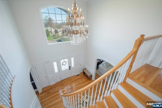 entryway featuring wood finished floors, plenty of natural light, a high ceiling, and an inviting chandelier