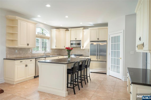 kitchen with decorative backsplash, a kitchen breakfast bar, a center island, stainless steel appliances, and a sink