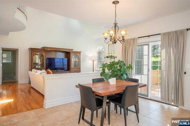 dining area with lofted ceiling, baseboards, a chandelier, and light tile patterned flooring