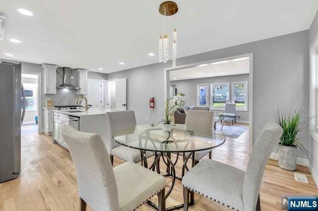 dining space featuring a healthy amount of sunlight, sink, and light hardwood / wood-style floors