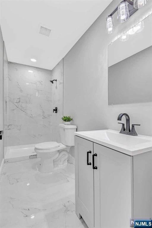 bathroom with vanity, toilet, and a tile shower