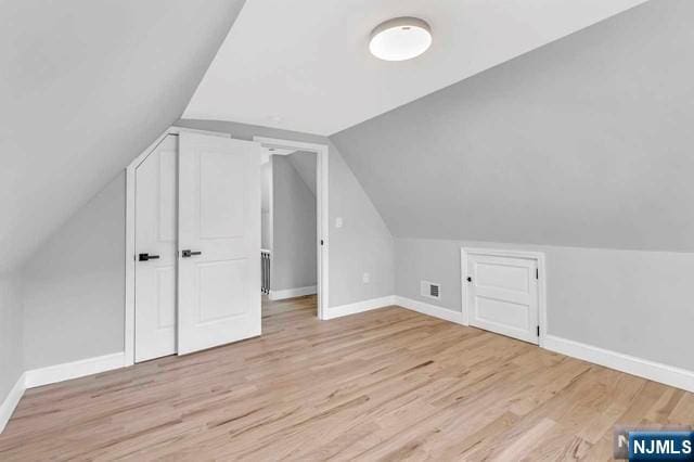 bonus room with lofted ceiling and light hardwood / wood-style flooring