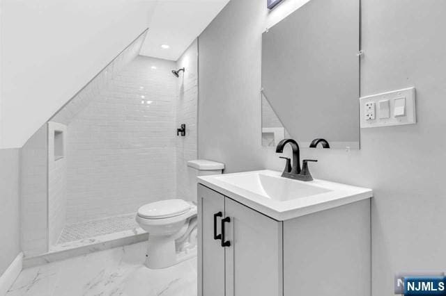 bathroom featuring vanity, toilet, and a tile shower