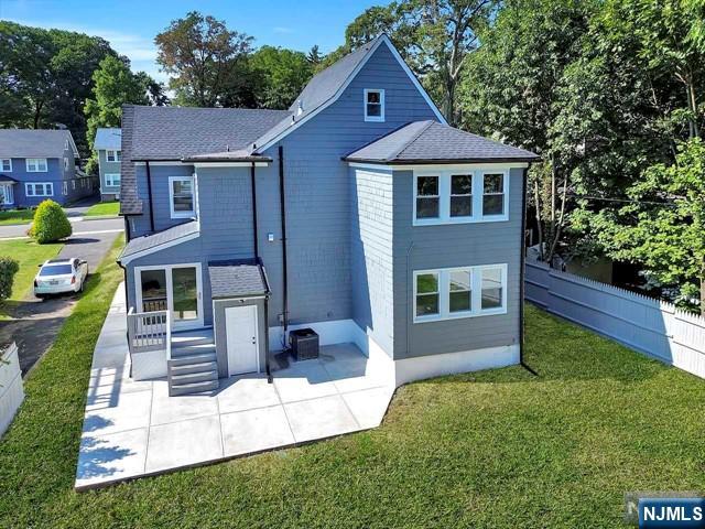 rear view of property with a patio, a yard, and central air condition unit