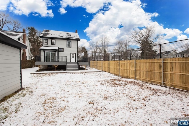 snow covered back of property featuring a deck