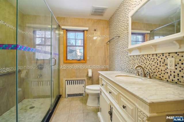 bathroom with tile patterned flooring, radiator heating unit, vanity, toilet, and walk in shower