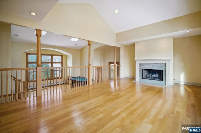 unfurnished living room featuring ceiling fan, a premium fireplace, high vaulted ceiling, and light hardwood / wood-style flooring