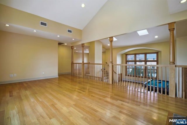 unfurnished room featuring ornate columns, high vaulted ceiling, and light hardwood / wood-style flooring