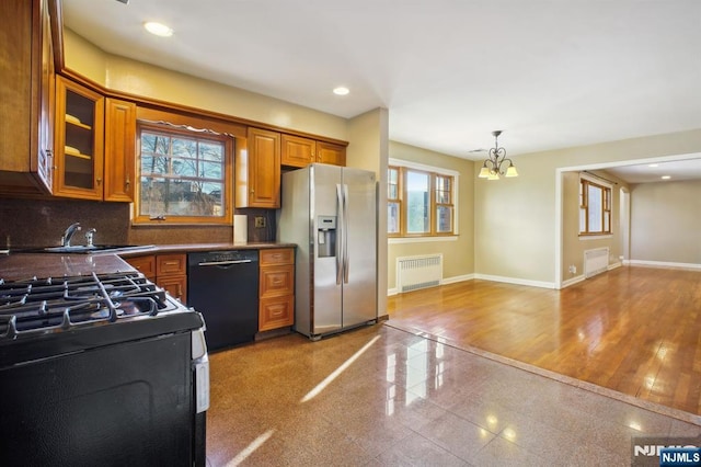 kitchen with radiator, sink, stainless steel fridge, backsplash, and black dishwasher