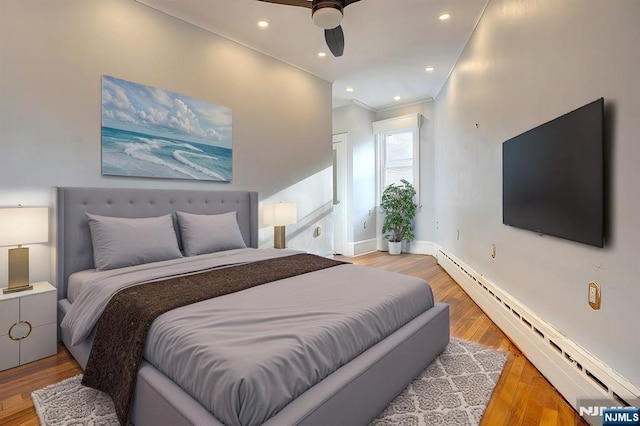 bedroom with a baseboard heating unit, wood-type flooring, ornamental molding, and ceiling fan