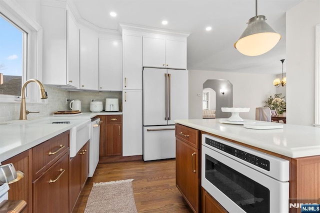 kitchen featuring sink, pendant lighting, white cabinetry, hardwood / wood-style flooring, and high end white fridge