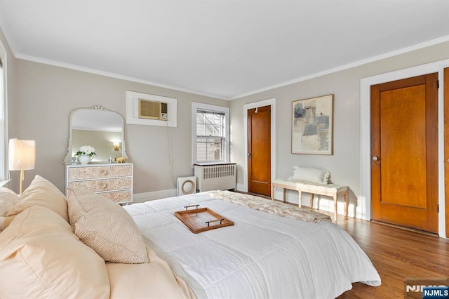 bedroom featuring hardwood / wood-style flooring, ornamental molding, radiator, and an AC wall unit