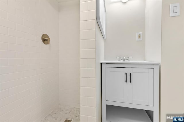 bathroom with vanity and a tile shower