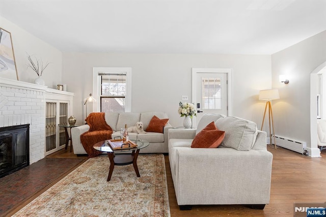 living room featuring dark hardwood / wood-style floors, a fireplace, and baseboard heating