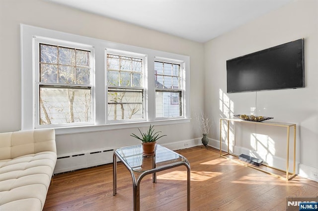 sitting room featuring hardwood / wood-style flooring, a healthy amount of sunlight, and baseboard heating