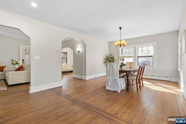 dining space featuring dark hardwood / wood-style flooring, a baseboard heating unit, and an inviting chandelier