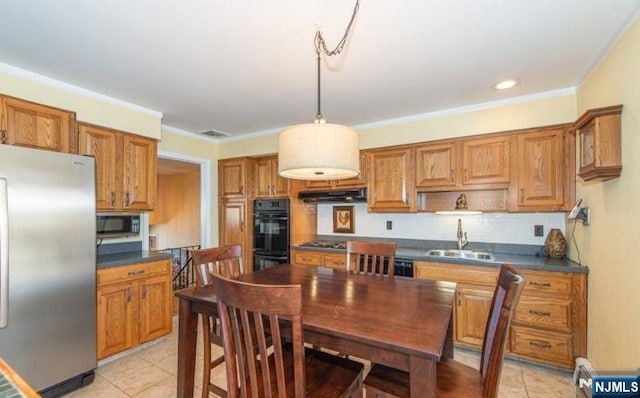 kitchen featuring decorative light fixtures, sink, a baseboard heating unit, light tile patterned floors, and stainless steel appliances