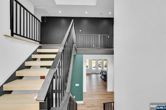 stairway featuring wood-type flooring, french doors, and a high ceiling