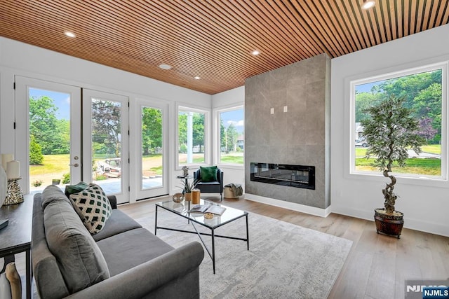 living room featuring a tiled fireplace, wooden ceiling, and light hardwood / wood-style floors