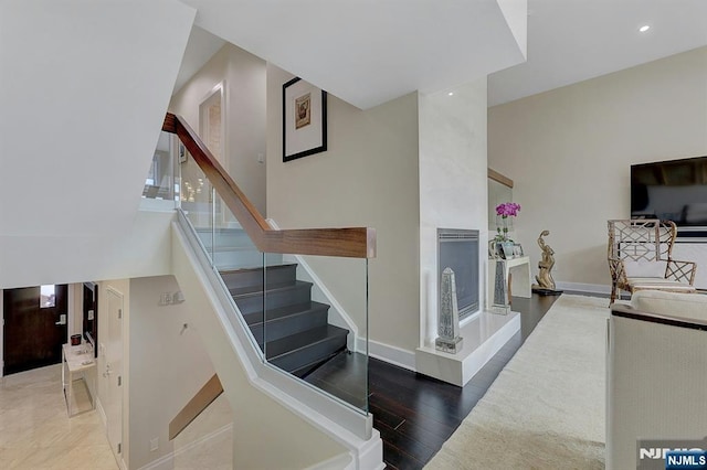 stairway featuring a fireplace, a towering ceiling, and wood-type flooring