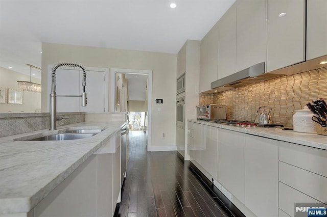 kitchen featuring dark wood-type flooring, sink, tasteful backsplash, stainless steel appliances, and white cabinets