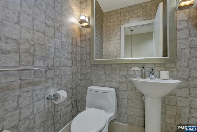 bathroom with tile walls and toilet