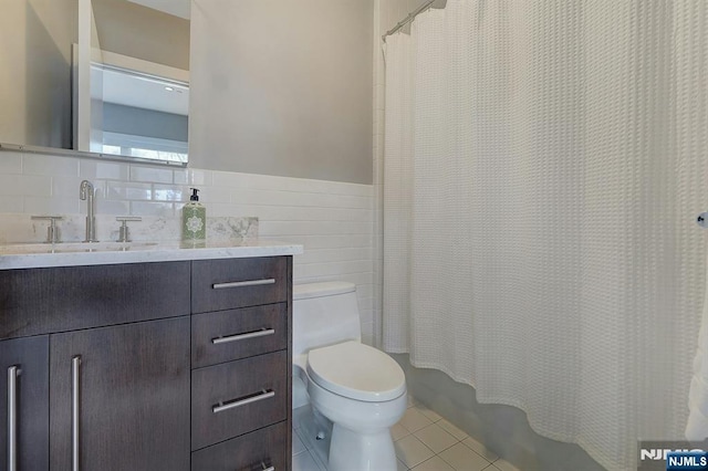 full bathroom featuring shower / tub combo with curtain, tile patterned flooring, tile walls, vanity, and toilet