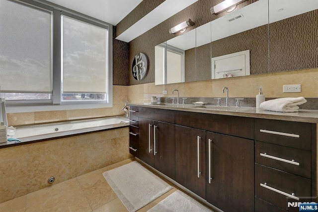 bathroom with tile patterned flooring, vanity, and tiled bath