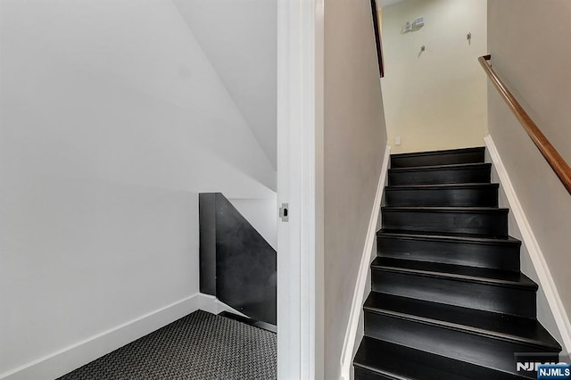 stairway featuring vaulted ceiling and carpet flooring