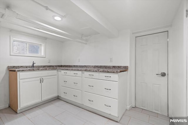 kitchen with white cabinetry, light tile patterned flooring, and sink