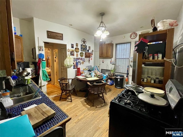 kitchen featuring sink, hanging light fixtures, light hardwood / wood-style floors, and gas stove