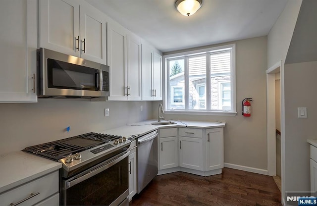 kitchen featuring stainless steel appliances, white cabinetry, sink, and dark hardwood / wood-style flooring