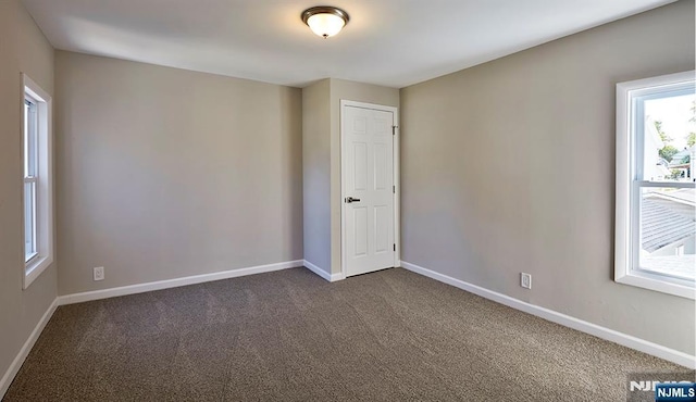 unfurnished room with dark carpet