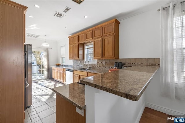 kitchen featuring sink, appliances with stainless steel finishes, dark stone countertops, hanging light fixtures, and kitchen peninsula