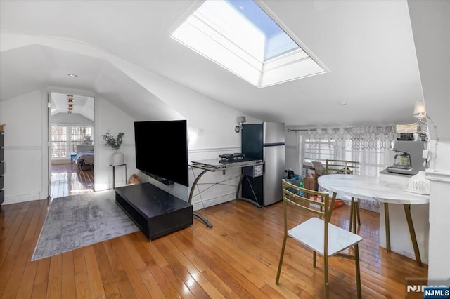 living room with wood-type flooring and vaulted ceiling with skylight