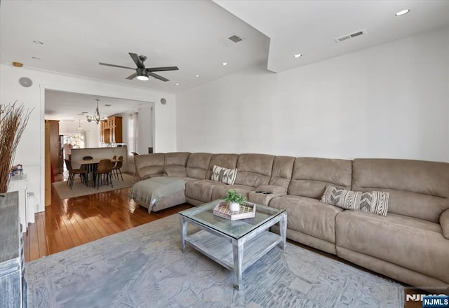 living room with wood-type flooring and ceiling fan with notable chandelier