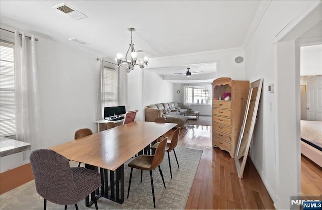 dining area with hardwood / wood-style floors, ornamental molding, and a chandelier