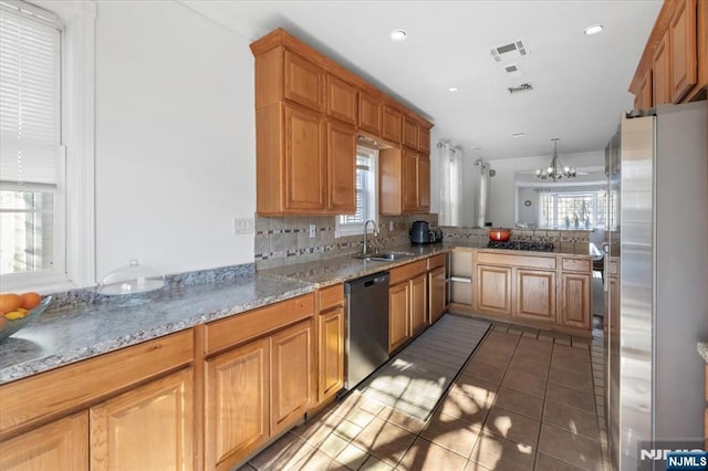 kitchen featuring sink, decorative light fixtures, kitchen peninsula, stainless steel appliances, and decorative backsplash