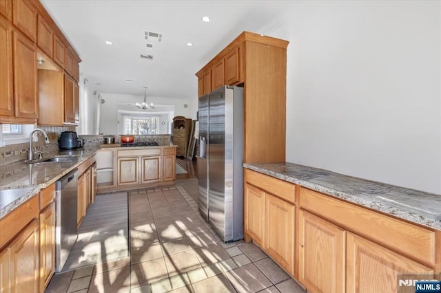 kitchen featuring appliances with stainless steel finishes, pendant lighting, sink, light tile patterned floors, and a notable chandelier