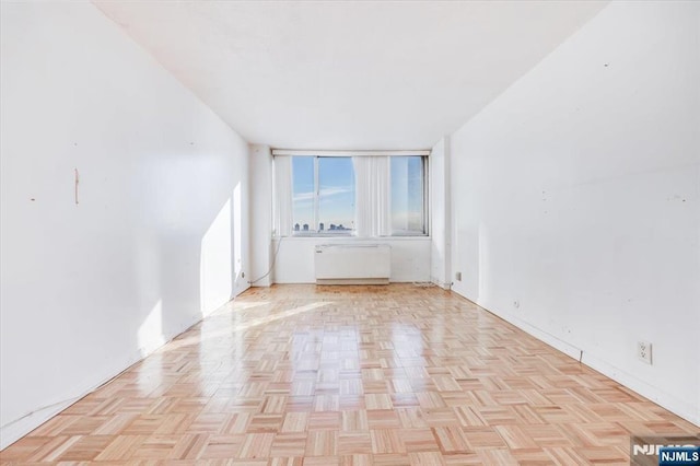 empty room featuring radiator and light parquet floors