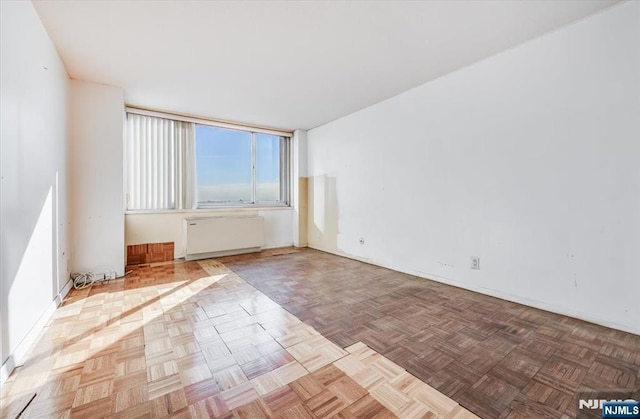 unfurnished room featuring light parquet flooring and radiator