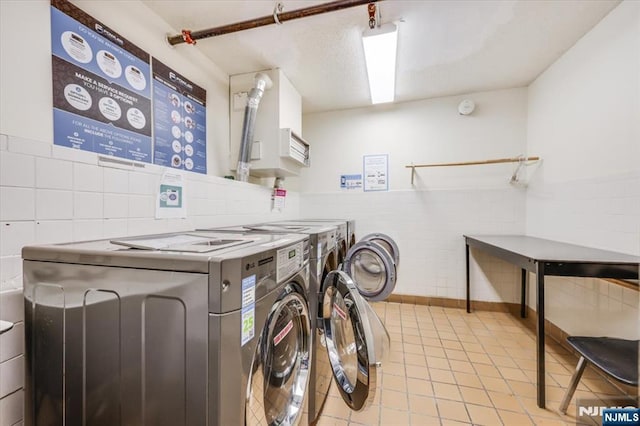 washroom with light tile patterned flooring, washing machine and clothes dryer, and tile walls