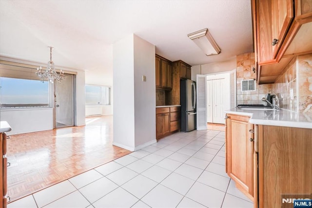 kitchen featuring sink, tasteful backsplash, hanging light fixtures, stainless steel fridge, and light parquet flooring